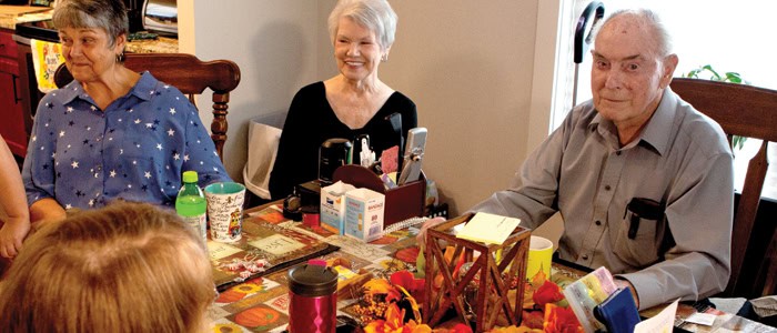 Three elderly people sitting a table together