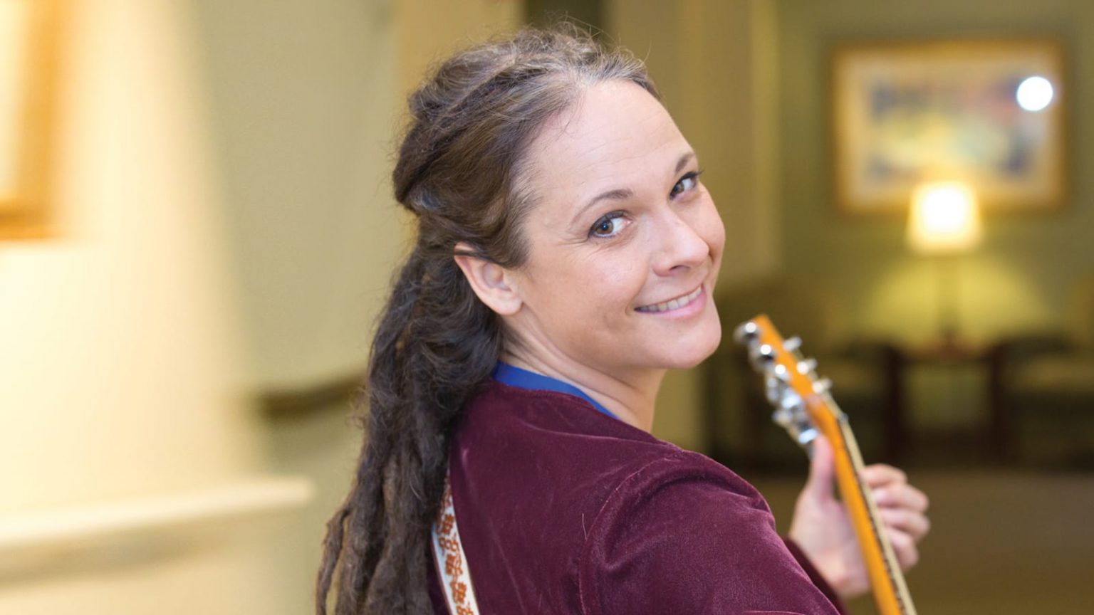 Volunteer smiling and holding guitar