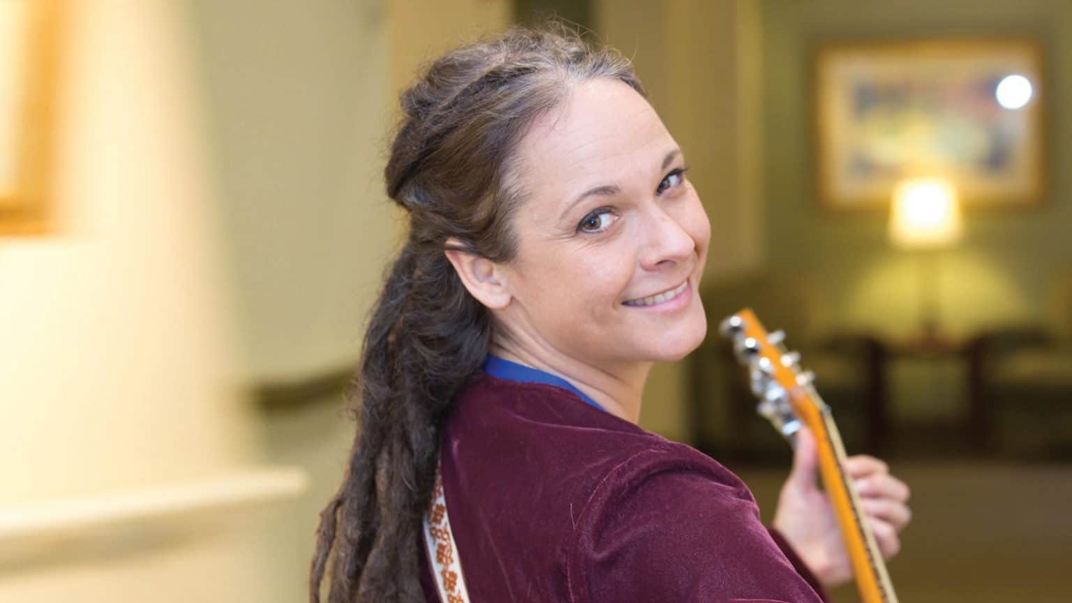 Volunteer smiling and holding guitar