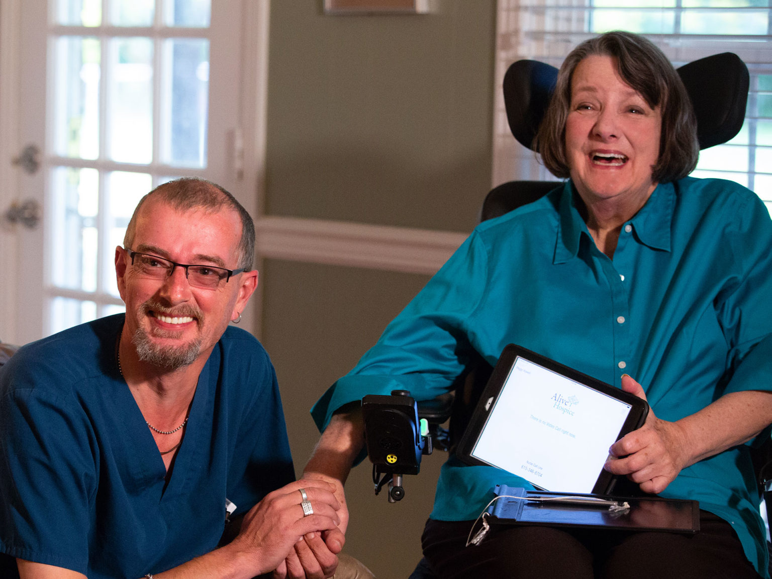 Woman in a wheelchair holding hands with a male hospice employee